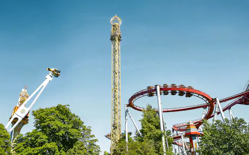 Tivoli Gardens roller coasters and rides against a clear blue sky in Copenhagen.
