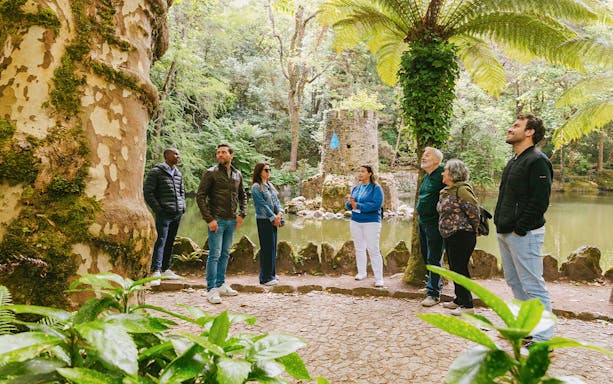 Group of tourists exploring gardens during Pena Palace guided tour in Sintra, Portugal.