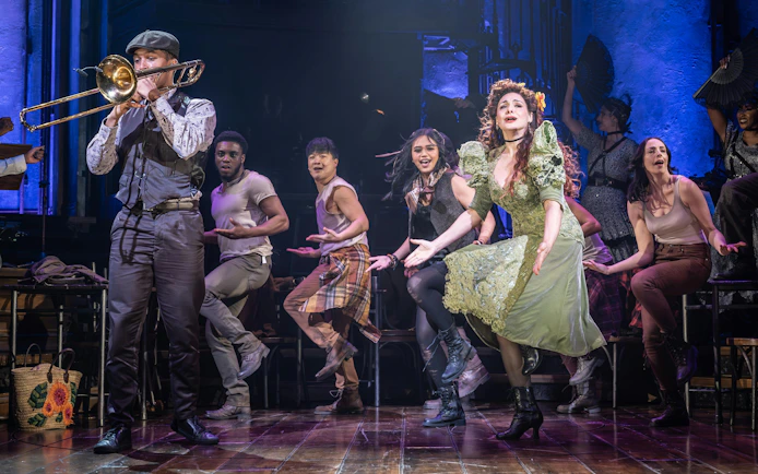 Stage performance of Hadestown in West End with actors singing and dancing.