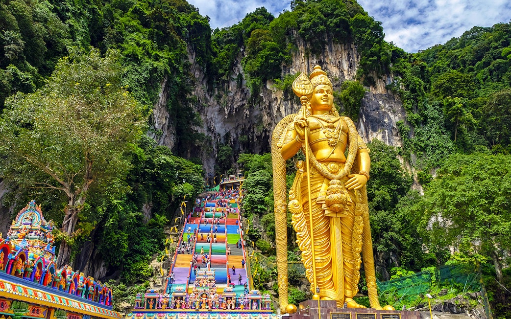 Golden Lord Murugan statue and colorful steps at Batu Caves, Malaysia.