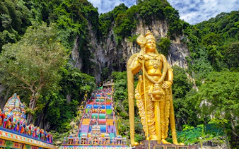 Golden Lord Murugan statue and colorful steps at Batu Caves, Malaysia.