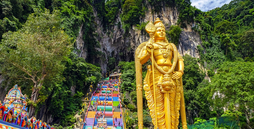 Golden Lord Murugan statue and colorful steps at Batu Caves, Malaysia.