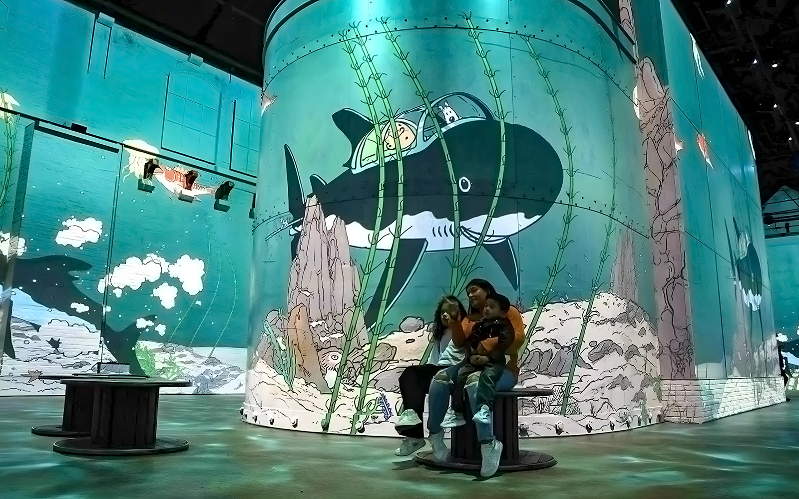 Family enjoying an immersive Tintin exhibition with submarine artwork in Brussels.
