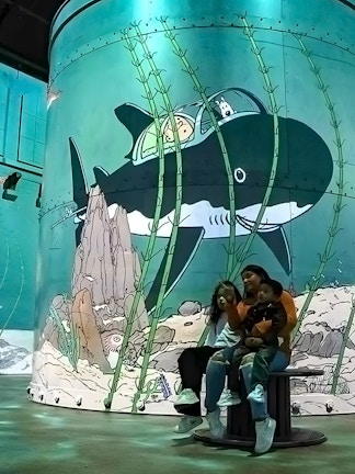 Family enjoying an immersive Tintin exhibition with submarine artwork in Brussels.