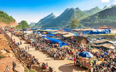 Bac Ha Market bustling with vendors and visitors, surrounded by scenic mountains in Vietnam.