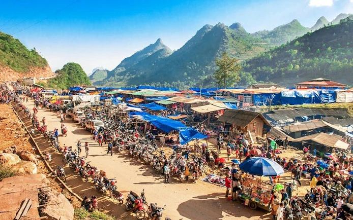Bac Ha Market bustling with vendors and visitors, surrounded by scenic mountains in Vietnam.