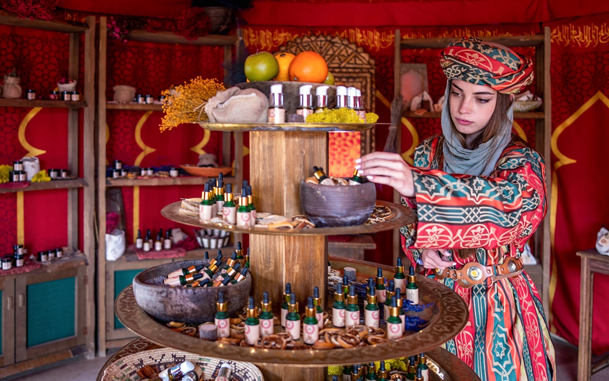 Woman examining products at Puy du Fou España market stall.