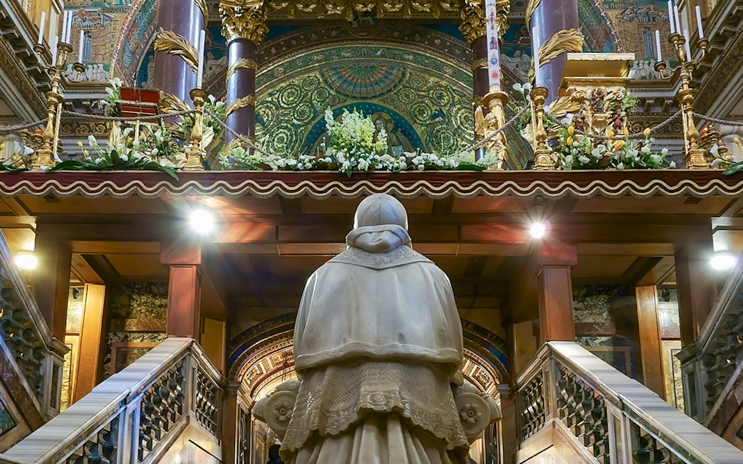 Statue in Santa Maria Maggiore's Crypt of the Nativity, Rome, with ornate altar above.