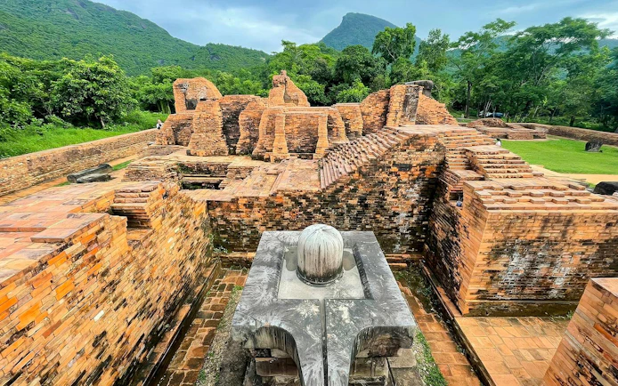 Ancient brick ruins at My Son Sanctuary, central Vietnam, surrounded by lush greenery and mountains.