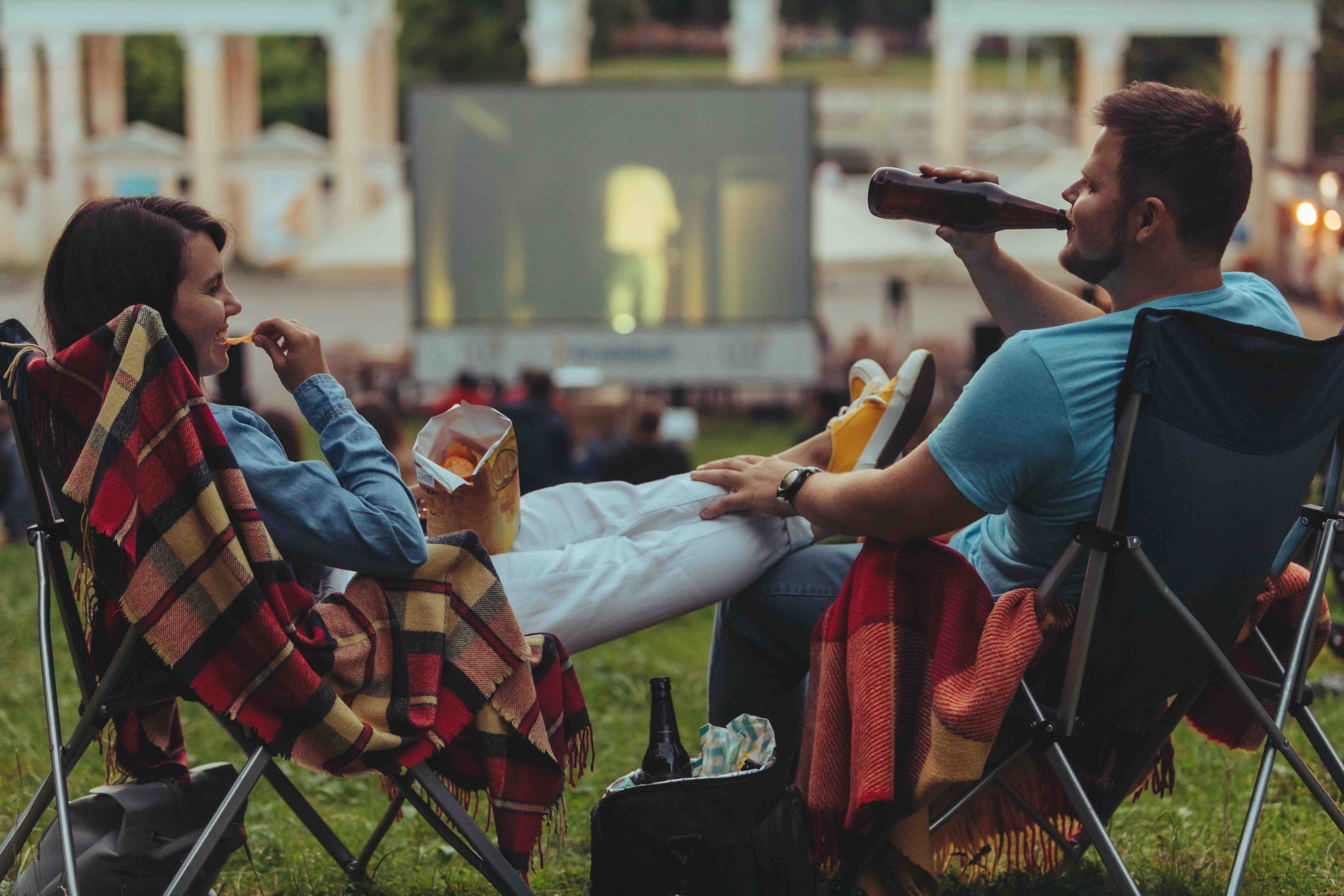 Outdoor cinema setup with large screen and seating in a scenic park setting, showcasing a unique movie experience.