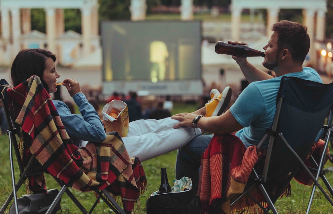 Outdoor cinema setup with large screen and seating in a scenic park setting, showcasing a unique movie experience.