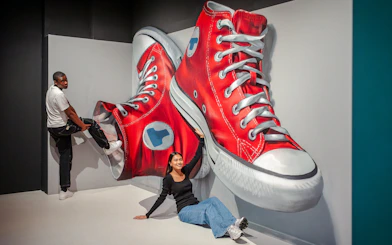 Guests interacting with giant sneaker art at Twist Museum in London.