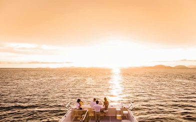 Sunset view from a boat on Split Riviera cruise with people enjoying drinks.