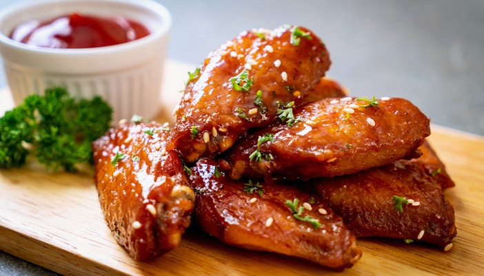 Chicken wings with fries and sauce on a plate, popular dish in New York City food tours.