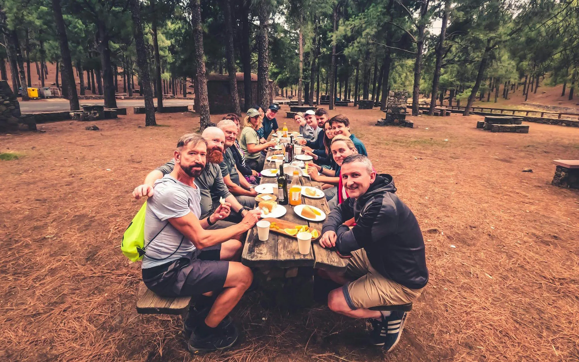 Group enjoying local food at a picnic table in a forest during Gran Canaria volcano sunset tour.