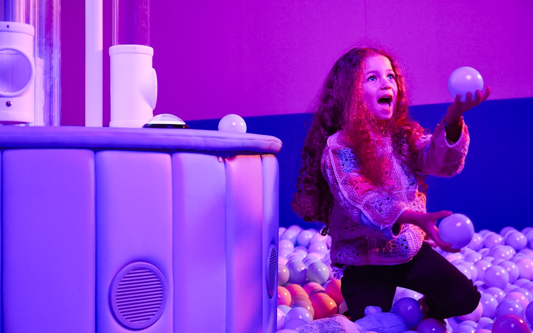 Child playing with balls at Bubble Planet exhibit, Washington DC.