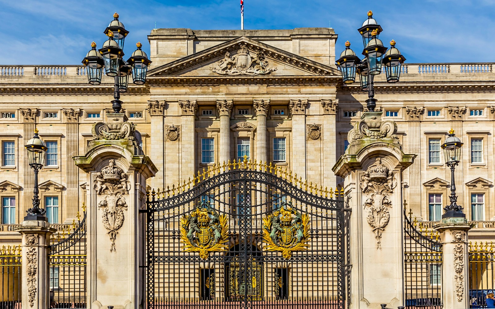 Buckingham Palace gates in London, featuring ornate crests and lampposts.