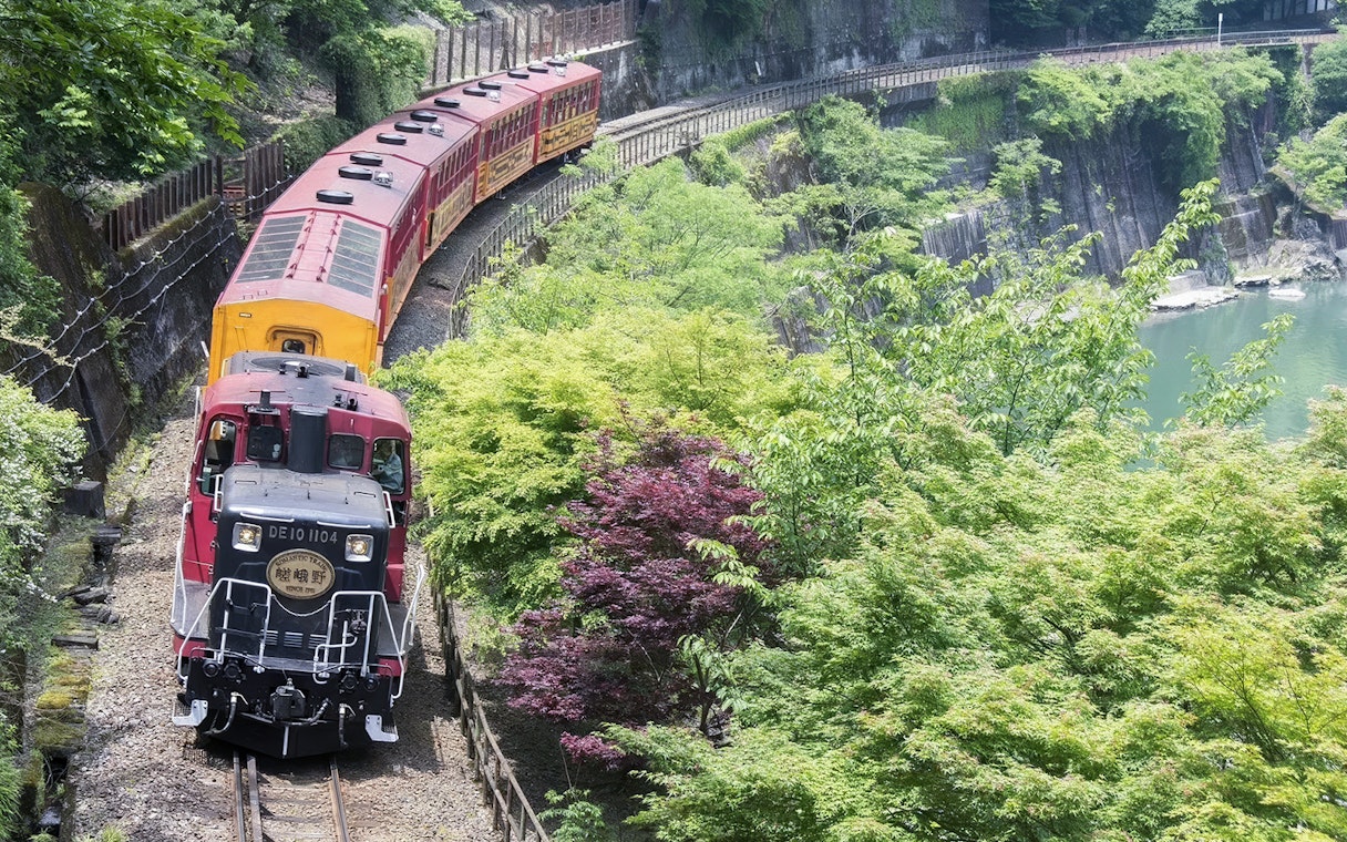 Sagano Romantic Train passing through lush greenery in Kyoto, Japan.