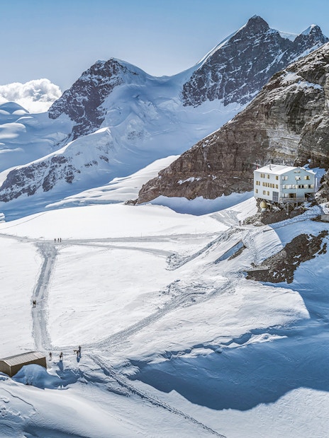 Jungfraujoch snowy landscape with mountain peaks and a building, seen on a day trip from Zürich.