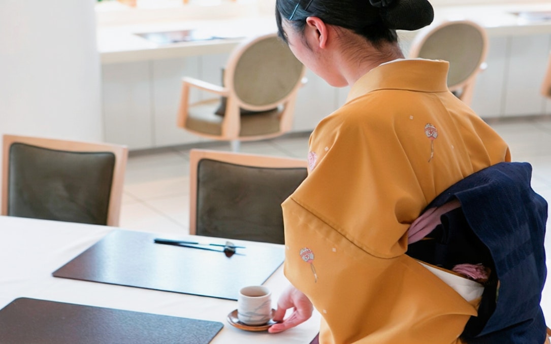 Server in kimono setting table at Tokyo Nadaman Nihonbashi branch for Omakase Kaiseki.