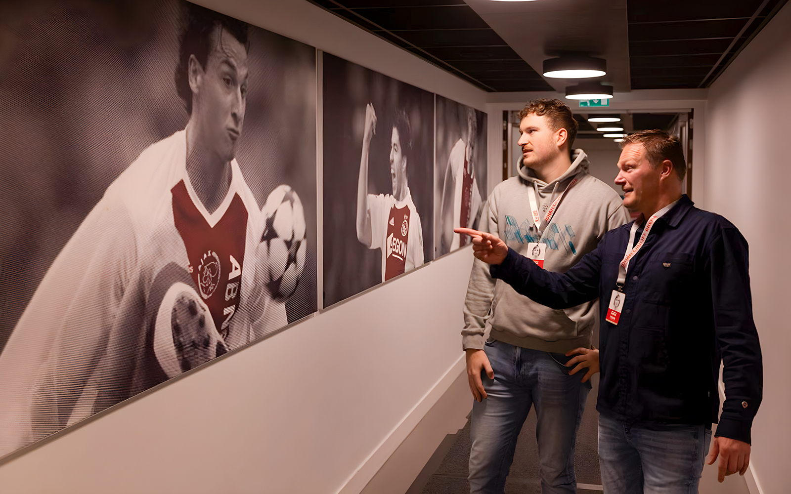 Visitors observing football player photos at Johan Cruijff ArenA tour.