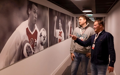 Visitors observing football player photos at Johan Cruijff ArenA tour.