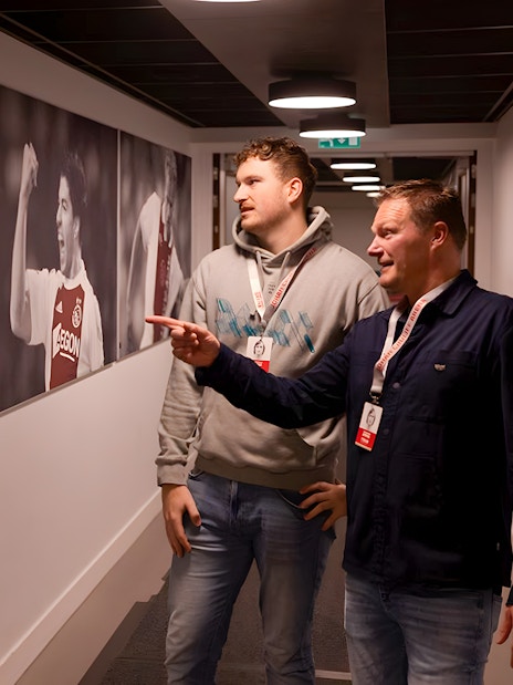 Visitors observing football player photos at Johan Cruijff ArenA tour.