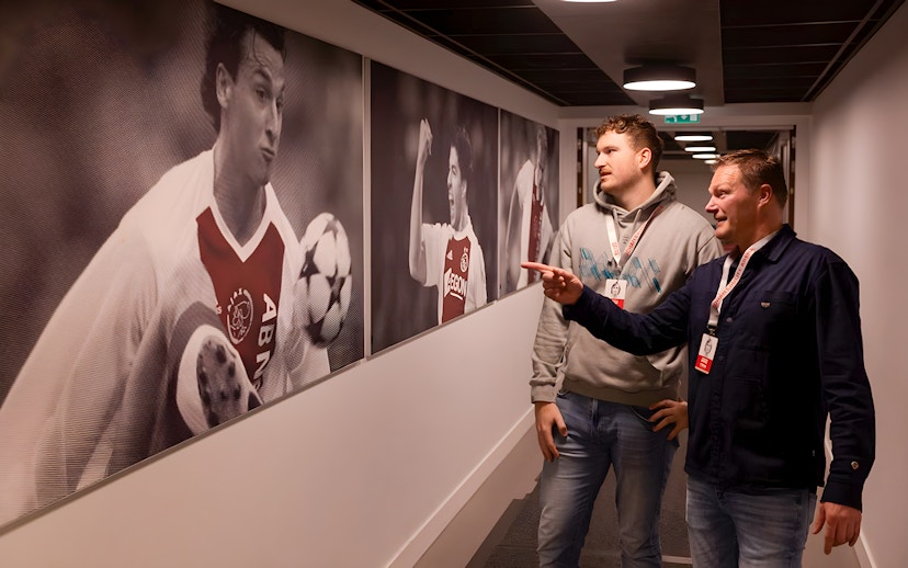 Visitors observing football player photos at Johan Cruijff ArenA tour.