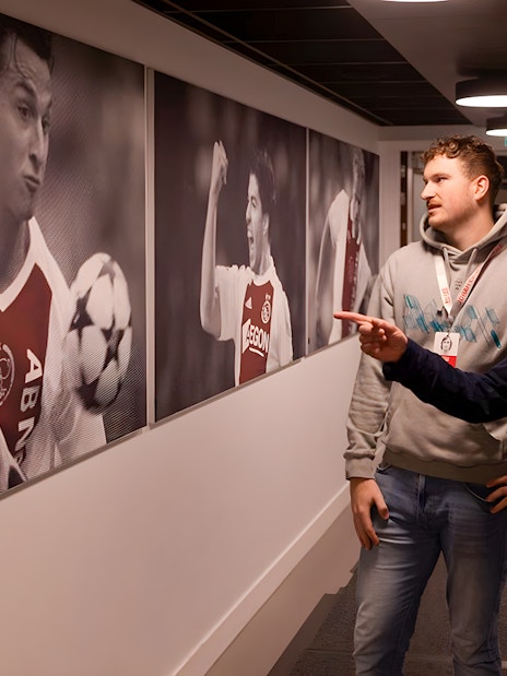 Visitors observing football player photos at Johan Cruijff ArenA tour.