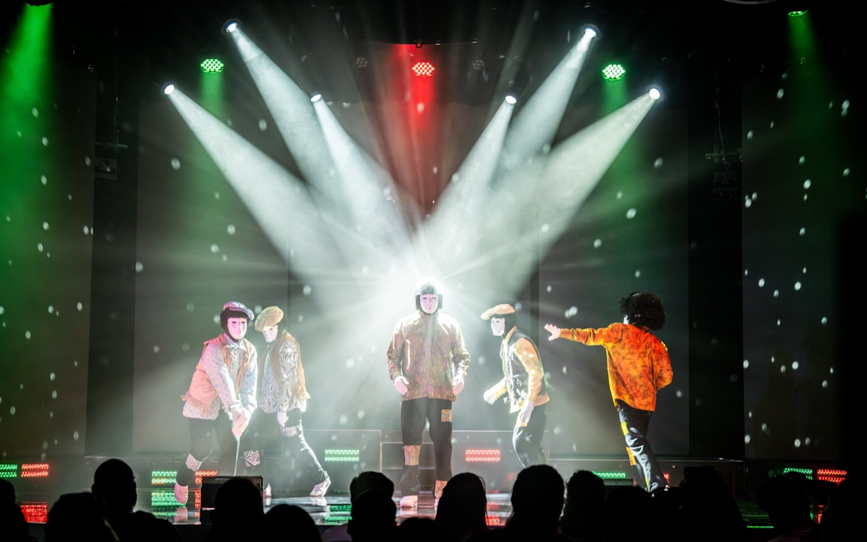 Jabbawockeez dancers performing on stage with dramatic lighting in Las Vegas show.