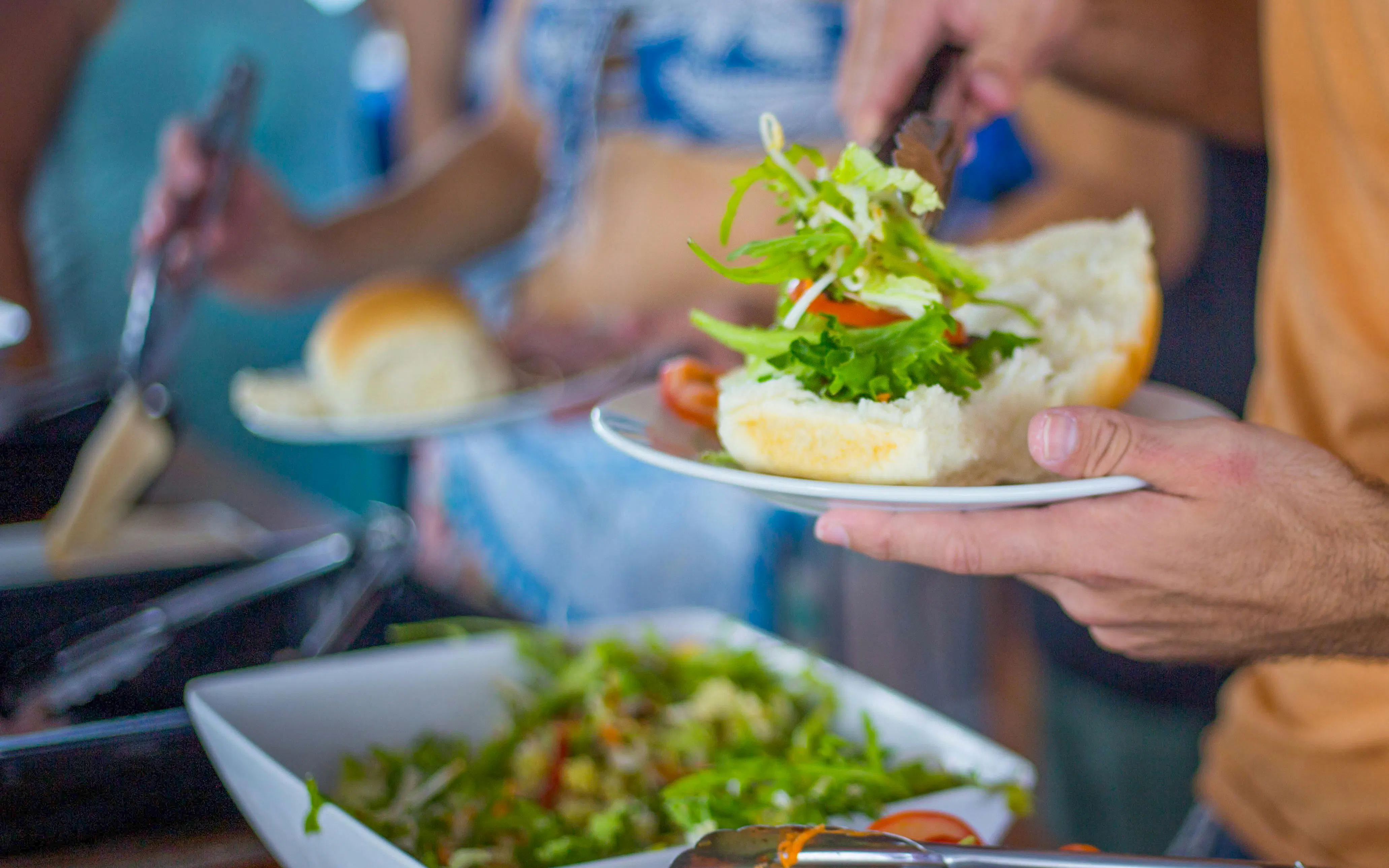 Preparing a sandwich with fresh salad during a Great Barrier Reef dive course lunch.
