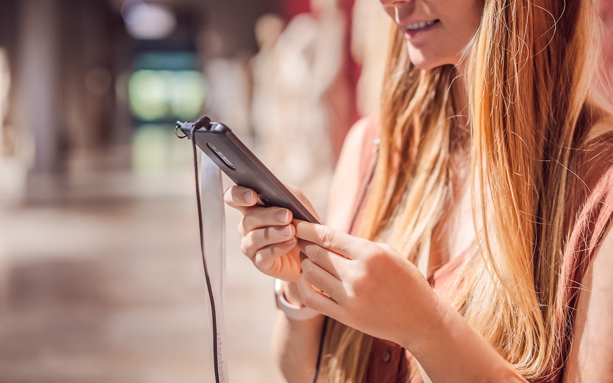 Woman using phone audio guide in a museum.