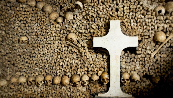 Skulls and bones arranged around a cross in the Paris Catacombs.