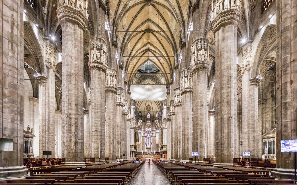 Duomo Milan Cathedral interior with tourists on guided tour, Italy.