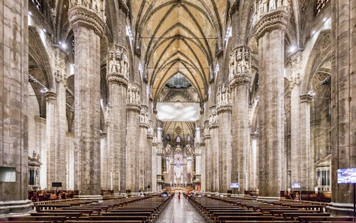Duomo Milan Cathedral interior with tourists on guided tour, Italy.