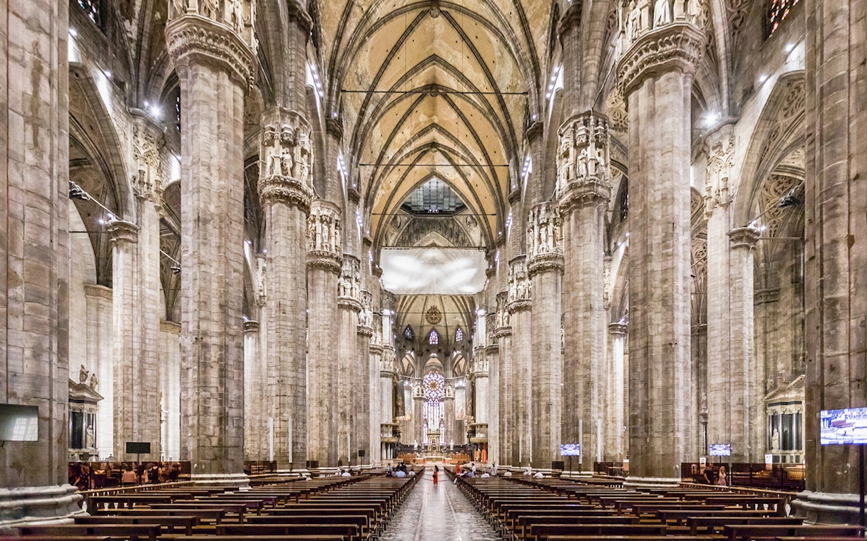 Duomo Milan Cathedral interior with tourists on guided tour, Italy.