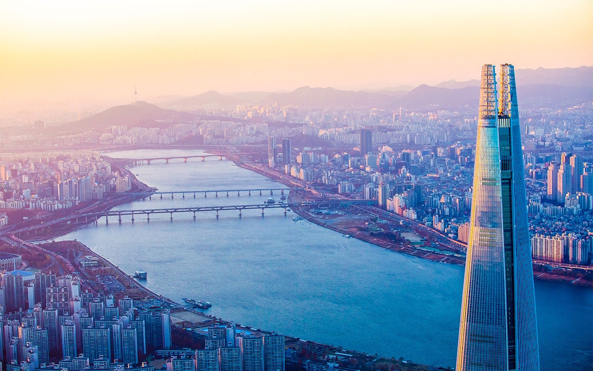 Lotte World Tower overlooking Han River in Seoul at sunset.