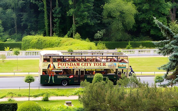 Potsdam city tour bus driving through a scenic park area.