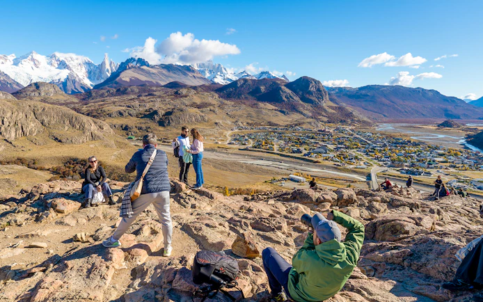 Tourists on a hiking trail overlooking El Chaltén village and mountains in Santa Cruz, Argentina.