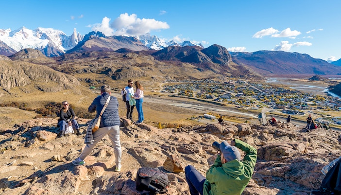 Tourists on a hiking trail overlooking El Chaltén village and mountains in Santa Cruz, Argentina.