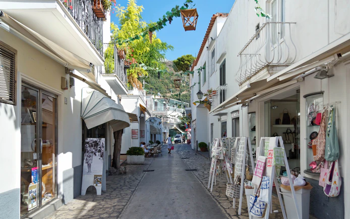 Narrow street in Anacapri Town with shops and hanging decorations.