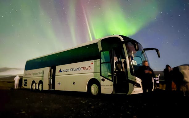 Coach parked under Northern Lights near Reykjavik, Iceland.