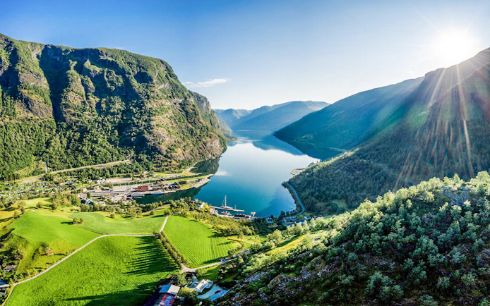 Flåm village nestled by Aurlandsfjord, surrounded by lush mountains and clear waters.