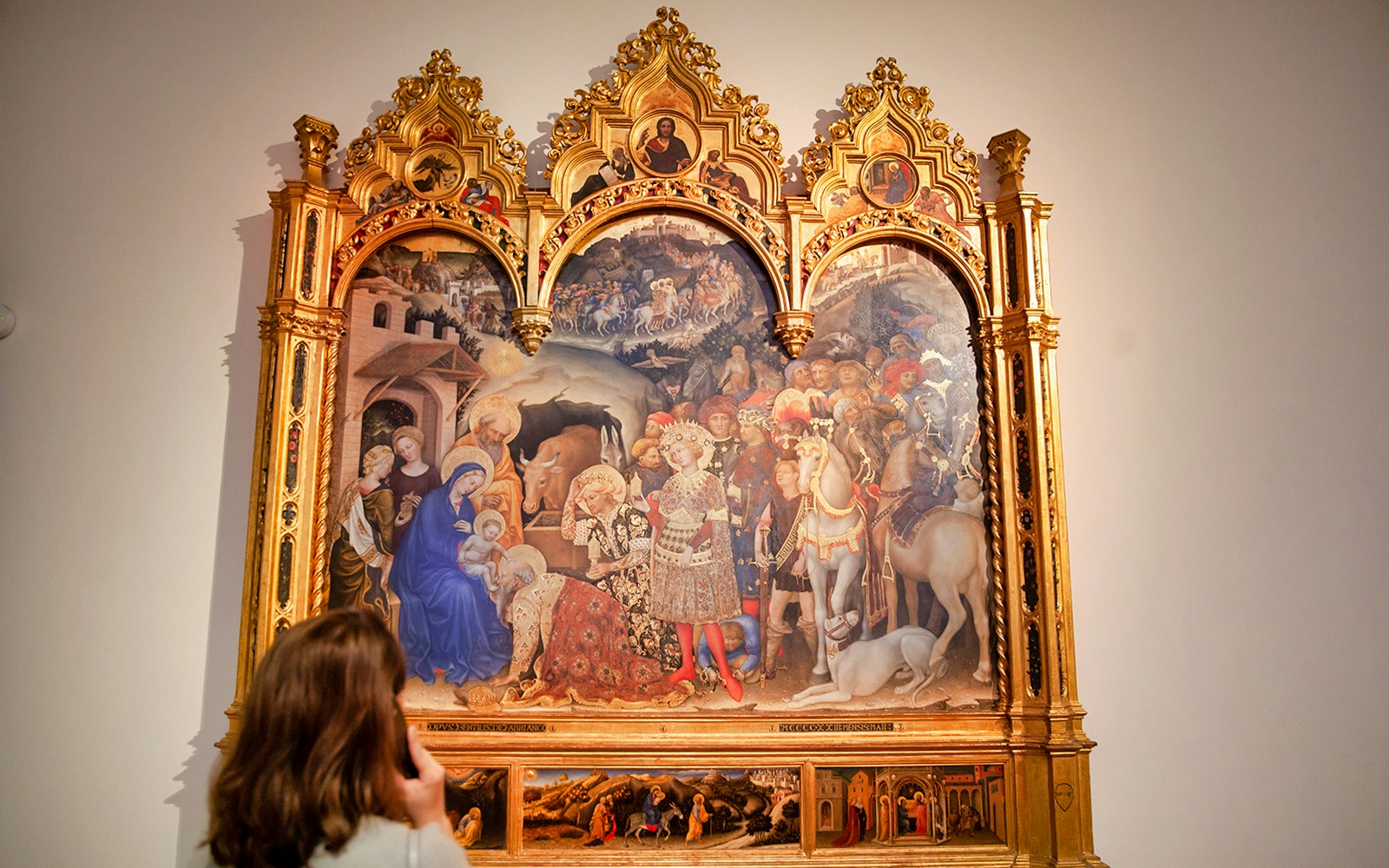 Visitor viewing the Adoration of the Magi painting in a museum setting.