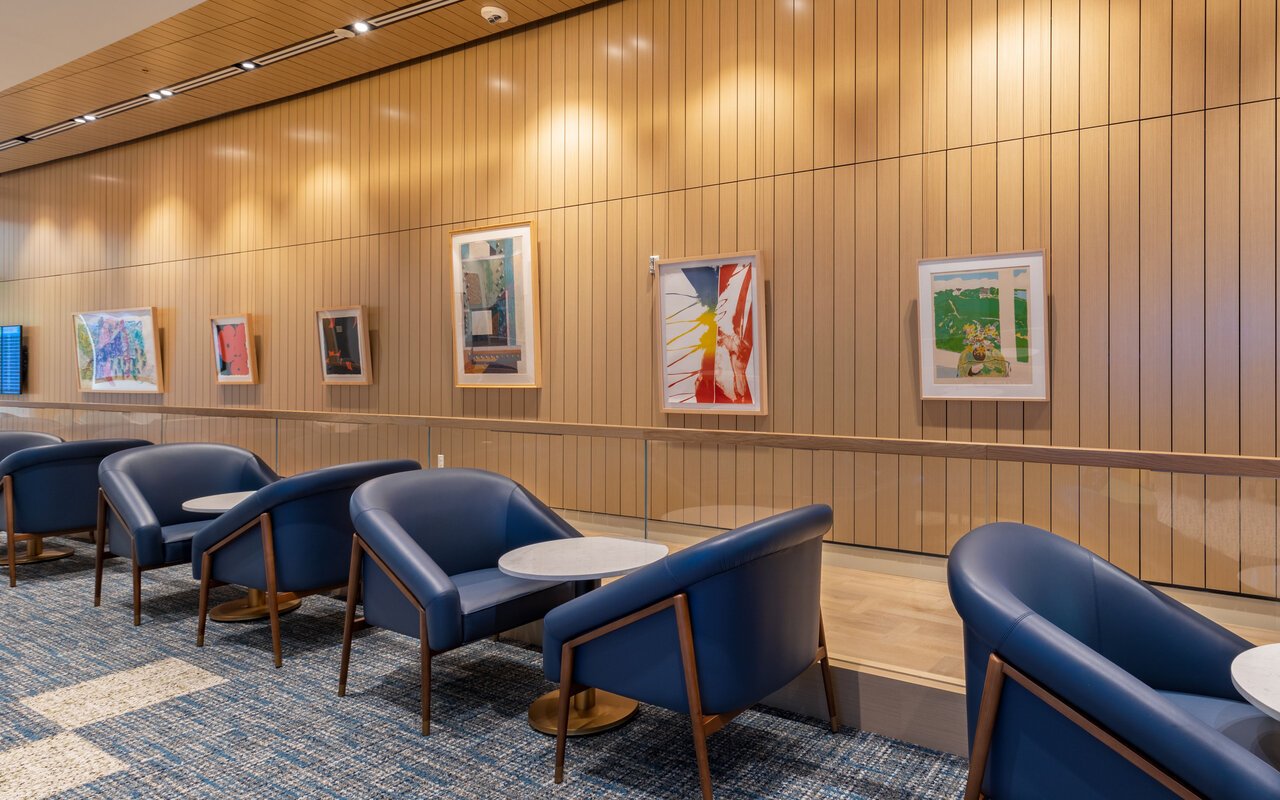 Seating area with blue chairs and art displays at Plaza Premium Lounge, Orlando Airport Terminal C.