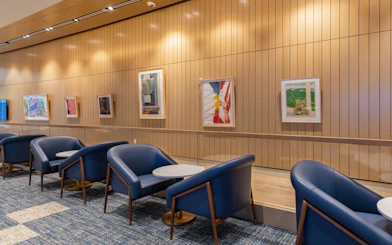 Seating area with blue chairs and art displays at Plaza Premium Lounge, Orlando Airport Terminal C.