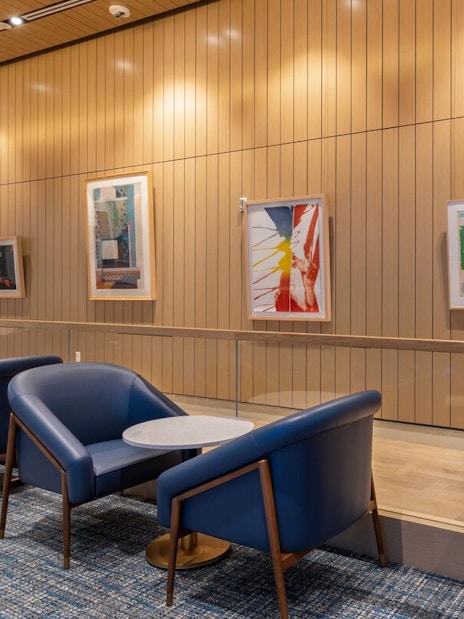 Seating area with blue chairs and art displays at Plaza Premium Lounge, Orlando Airport Terminal C.