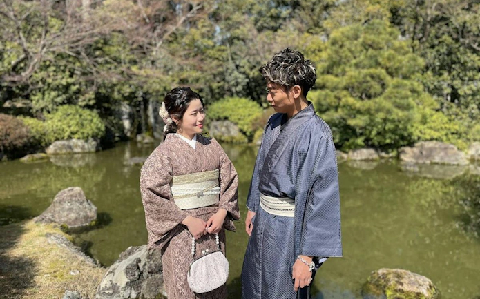 Men and women in traditional kimonos by a pond in Kyoto garden.