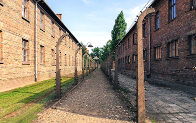 Barbed wire fence and brick buildings at Auschwitz sub-camp, Poland.