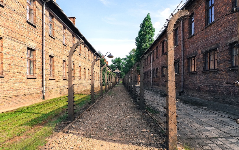 Barbed wire fence and brick buildings at Auschwitz sub-camp, Poland.